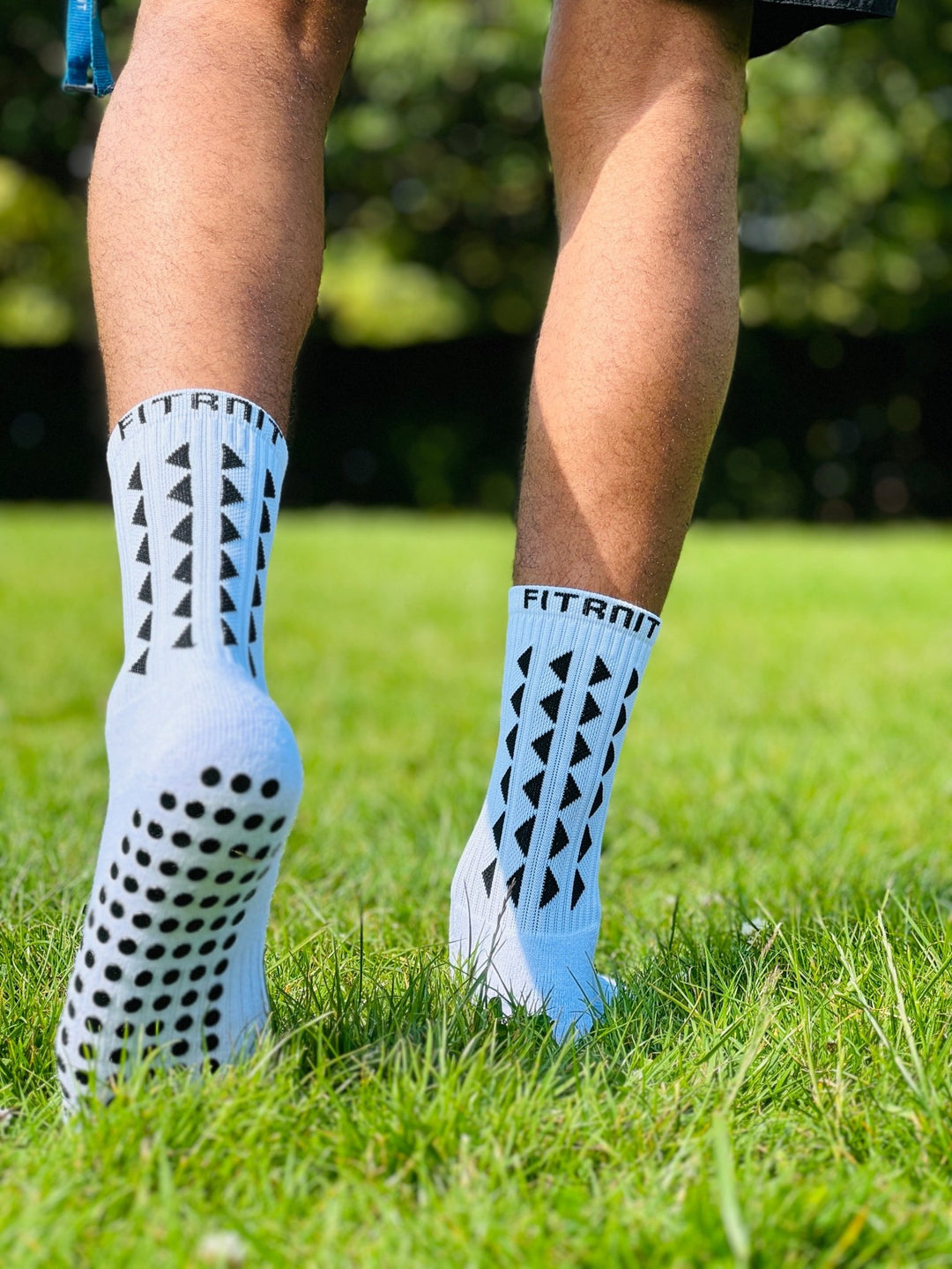 Fitknitsocks white grip socks providing stability and comfort outdoors, worn by an athlete on grass