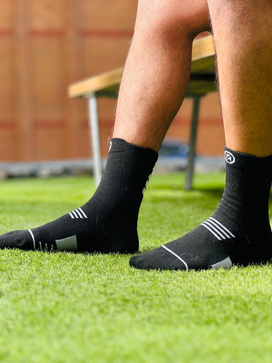 Close-up of Fitknitsocks black grip socks worn by a person standing on grass